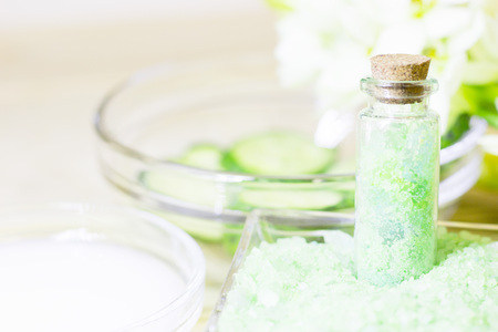 Cucumber home spa and hair care concept. Sliced cucumber, bottles of oil, bathroom towel. Straw light background. Closeupの写真素材
