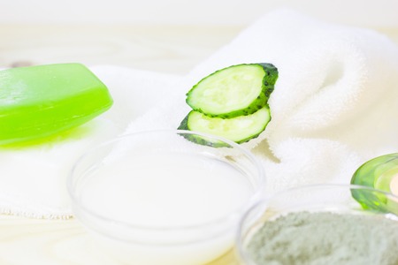 Cucumber home spa and hair care concept. Sliced cucumber, bottles of oil, sea salt, bathroom towel. White board background. Closeupの写真素材
