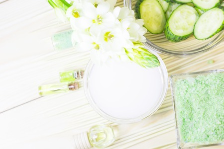 Cucumber home spa and hair care concept. Sliced cucumber, bottles of oil, sea salt, bathroom towel. Straw light background. Closeupの写真素材