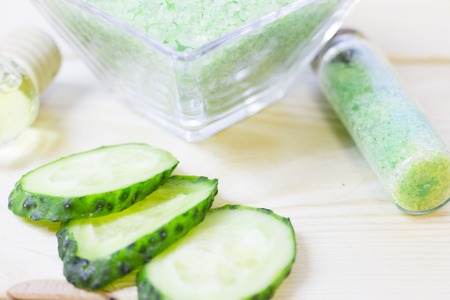 Cucumber home spa and hair care concept. Sliced cucumber, bottles of oil, sea salt, bathroom towel. White board background. Closeupの写真素材
