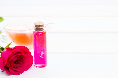 Spa and wellness setting with rose flower, sea salt, oil in a bottle on wooden white background closeupの写真素材