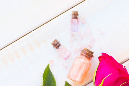 Spa and wellness setting with rose flower, sea salt, oil in a bottle on wooden white background closeupの写真素材