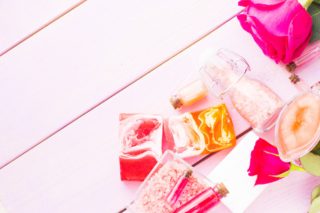 Spa and wellness setting with rose flower, sea salt, oil in a bottle on wooden white background...