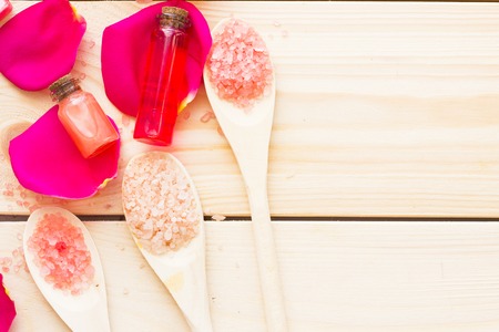 Spa and wellness setting with rose flower, sea salt, oil in a bottle on wooden old background closeupの写真素材