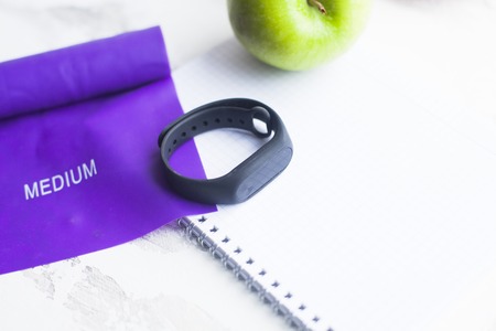 Time for diet slimming weight loss concept. Sport fitness, apple, sneakers, bottle of water and yellow weights on white wooden background.の写真素材