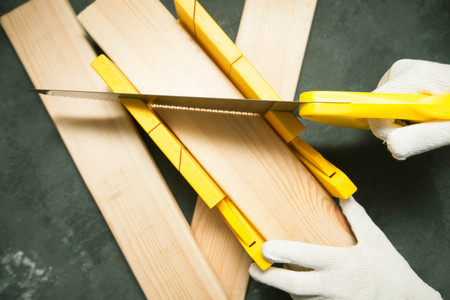 Repair modern tools: saw in man hands on dark stone background, top view, copy space