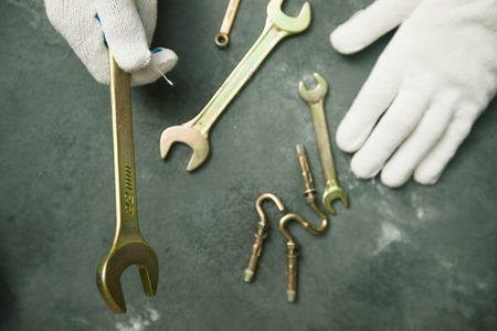 Repair modern tools: man hands in gloves on dark stone background, top view, copy spaceの写真素材