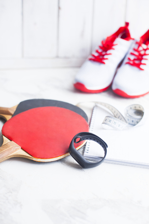 Sport fitness, weight loss concept. racket, balls, notepad, sneakers on white wooden background. Vintage retro filterの写真素材