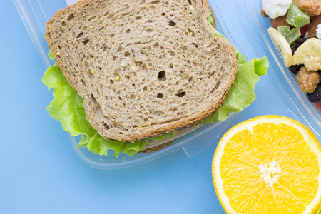 School lunch box. Bread, orange, candies, baby corns, carrot and tomatoes in green plastic...