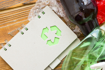 Environmental protection, ecology and recycling concept, recycle sign, notepad and garbage on dark...