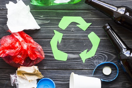 Environmental protection, ecology and recycling concept, recycle sign and garbage on dark wooden...