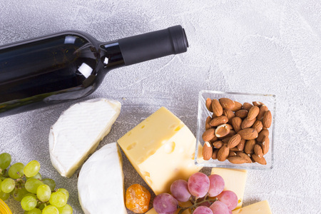 Snacks with wine - bottle, various types of cheeses, figs, nuts, honey, grapesの写真素材