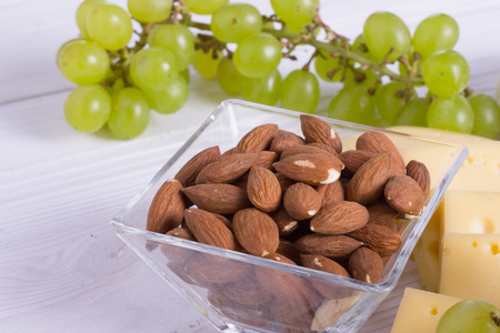 Snacks with wine - various types of cheeses, figs, nuts, honey, grapes on a white boards backgroundの写真素材