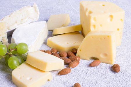Snacks with wine - various types of cheeses, figs, nuts, honey, grapes on a white wooden backgroundの写真素材