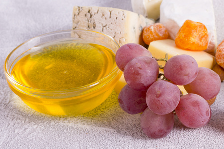 Snacks with wine - various types of cheeses, figs, nuts, honey, grapes on a white wooden backgroundの写真素材