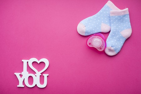 Newborn baby story. Socks and children's toys, scissors, baby bottle, nipple, hairbrush on red background. Top viewの写真素材