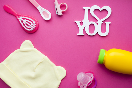 Newborn baby story. Socks and children's toys, scissors, baby bottle, nipple, hairbrush on red background. Top viewの写真素材