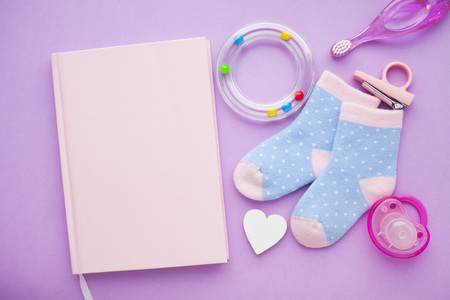 Newborn baby story. Strow heart and children's toys, scissors, baby bottle, nipple, hairbrush on violet background. Top viewの写真素材
