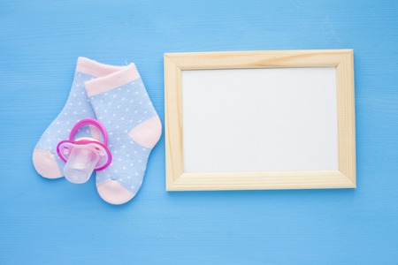 Newborn baby story. Frame with copyspace and children's toys, scissors, baby bottle, nipple, hairbrush on blue background. Top viewの写真素材