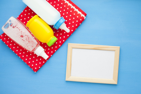Newborn baby story. Frame with copyspace and children's toys, scissors, baby bottle, nipple, hairbrush on blue background. Top viewの写真素材