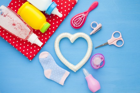 Newborn baby story. Children's toys, scissors, baby bottle, nipple, hairbrush on red background. Top viewの写真素材