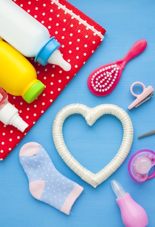 Newborn baby story. Children's toys, scissors, baby bottle, nipple, hairbrush on red background. Top viewの素材 [FY310121660862]