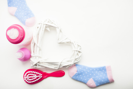 Newborn baby story. Strow heart and children's toys, scissors, baby bottle, nipple, hairbrush on white background. Top viewの写真素材