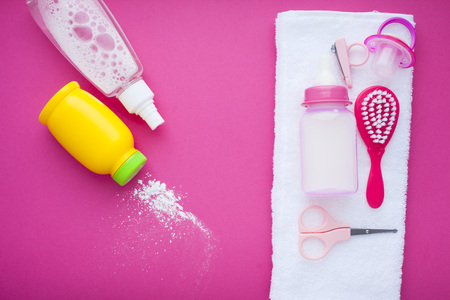 Newborn baby story. Towels and children's toys, scissors, baby bottle, nipple, hairbrush on red background. Top viewの写真素材