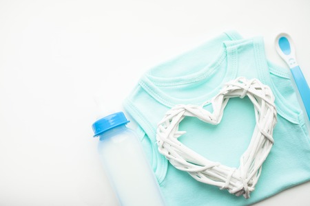 Newborn baby story. T-shirt and children's toys, scissors, baby bottle, nipple, hairbrush on white background. Top viewの写真素材