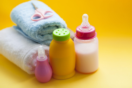 Newborn baby story. Towels and children's toys, scissors, baby bottle, nipple, hairbrush on yellow background. Top viewの写真素材