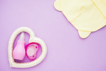 Newborn baby story. Strow heart and children's toys, scissors, baby bottle, nipple, hairbrush on violet background. Top viewの写真素材