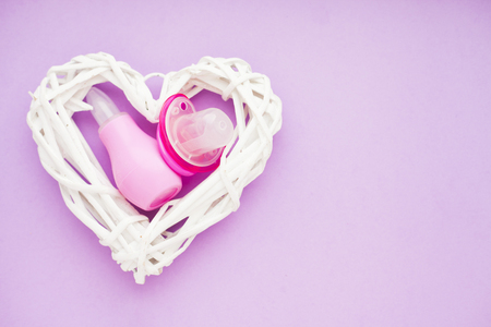 Newborn baby story. Strow heart and children's toys, scissors, baby bottle, nipple, hairbrush on violet background. Top viewの写真素材