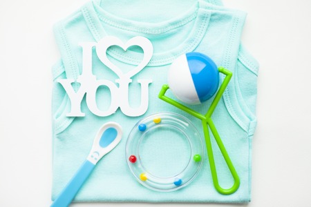 Newborn baby story. T-shirt and children's toys, scissors, baby bottle, nipple, hairbrush on white background. Top viewの写真素材