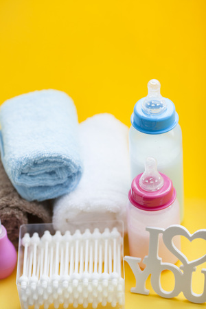 Newborn baby story. Towels and children's toys, scissors, baby bottle, nipple, hairbrush on yellow background. Top viewの写真素材