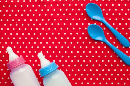 Newborn baby story. Children's toys, scissors, baby bottle, nipple, hairbrush on red background. Top viewの写真素材
