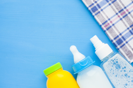 Newborn baby story. Children's toys, scissors, baby bottle, nipple, hairbrush on blue background. Top viewの写真素材
