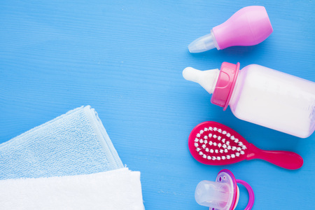 Newborn baby story. Towels and children's toys, scissors, baby bottle, nipple, hairbrush on blue background. Top viewの写真素材