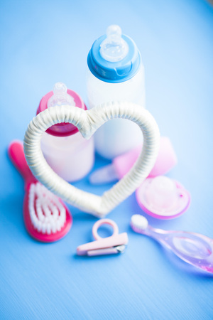 Newborn baby story. Children's toys, scissors, baby bottle, nipple, hairbrush on blue background. Top viewの写真素材