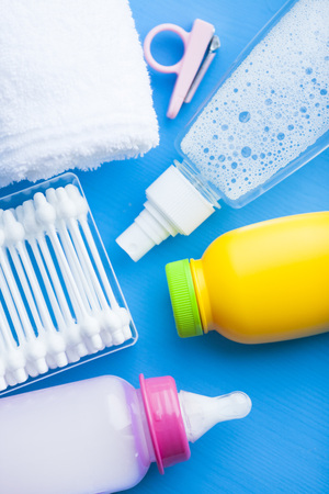 Newborn baby story. Towels and children's toys, scissors, baby bottle, nipple, hairbrush on blue background. Top viewの写真素材