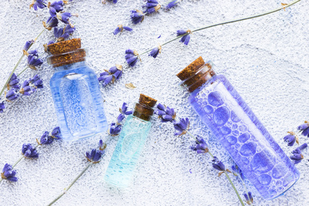 Spa and wellness setting with lavender flowers, sea salt, oil in a bottle, aroma candle on wooden white background closeupの写真素材