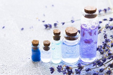 Spa and wellness setting with lavender flowers, sea salt, oil in a bottle, aroma candle on wooden white background closeupの写真素材