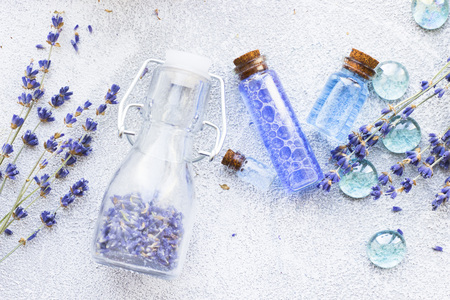 Spa and wellness setting with lavender flowers, sea salt, oil in a bottle, aroma candle on wooden white background closeupの写真素材