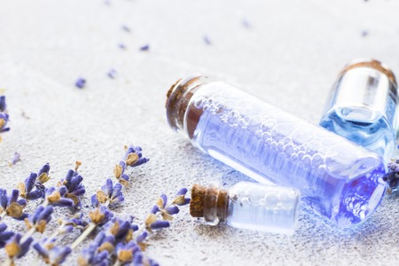 Spa and wellness setting with lavender flowers, sea salt, oil in a bottle, aroma candle on wooden white background closeupの写真素材