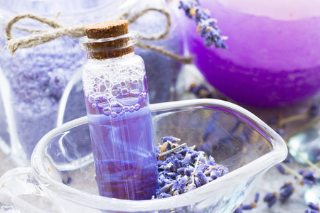 Spa and wellness setting with lavender flowers, sea salt, oil in a bottle, aroma candle on wooden white background closeupの写真素材