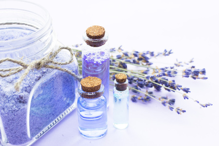 Spa and wellness setting with lavender flowers, sea salt, oil in a bottle, aroma candle on wooden white background closeupの写真素材