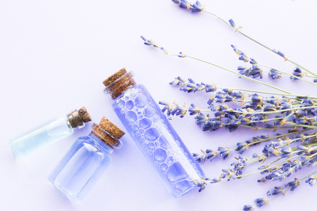 Spa and wellness setting with lavender flowers, sea salt, oil in a bottle, aroma candle on wooden white background closeupの写真素材