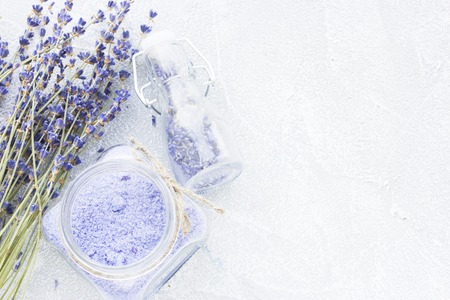 Spa and wellness setting with lavender flowers, sea salt, oil in a bottle, aroma candle on wooden white background closeupの写真素材