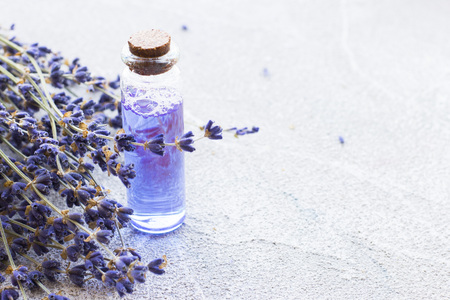 Spa and wellness setting with lavender flowers, sea salt, oil in a bottle, aroma candle on wooden white background closeupの写真素材