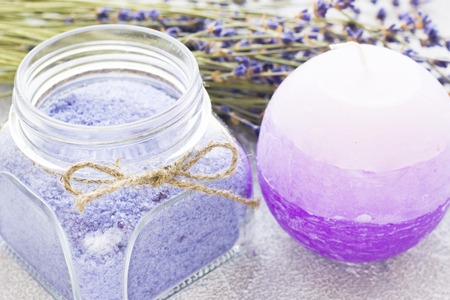 Spa and wellness setting with lavender flowers, sea salt, oil in a bottle, aroma candle on wooden white background closeupの写真素材
