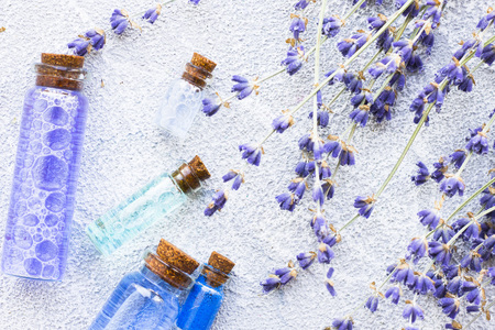 Spa and wellness setting with lavender flowers, sea salt, oil in a bottle, aroma candle on wooden white background closeupの写真素材